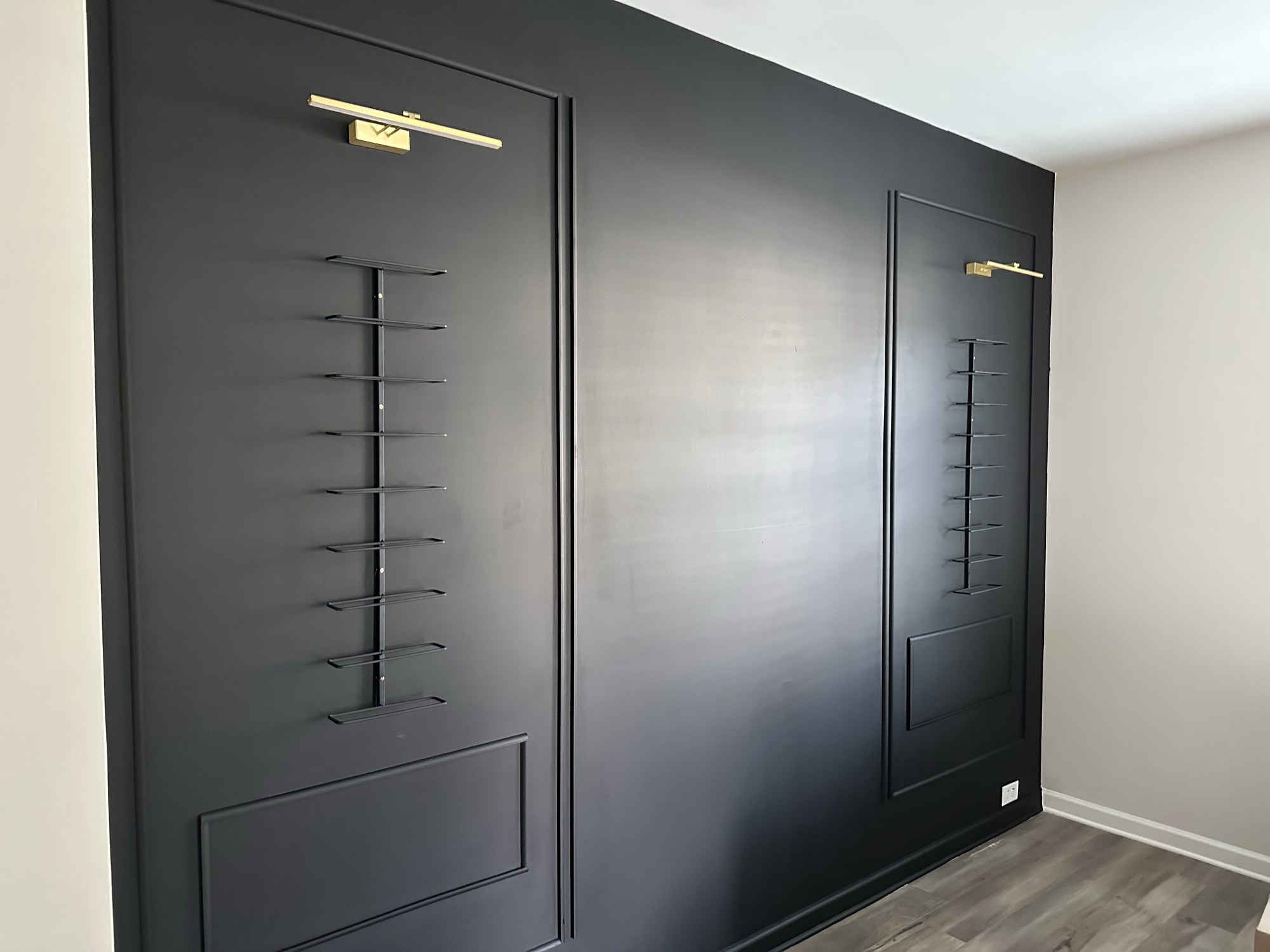 Custom black wine rack wall with brass sconces
