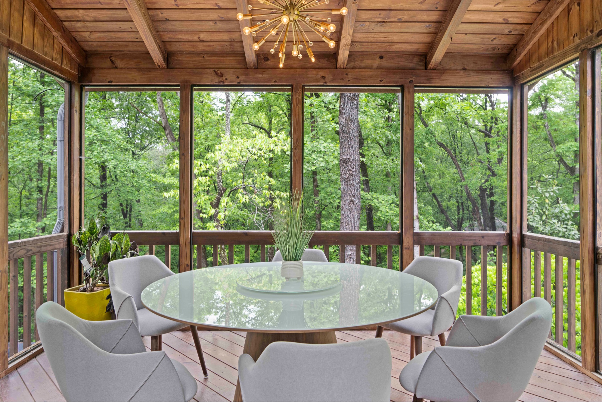 Screened porch with round glass dining table and sputnik chandelier